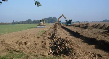 Planierraupe und Brecher beim Wegebau zwischen Feldern