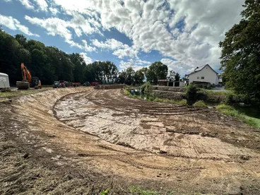 Neu modellierte Uferböschung an einem Flusslauf mit Bagger und Traktoren